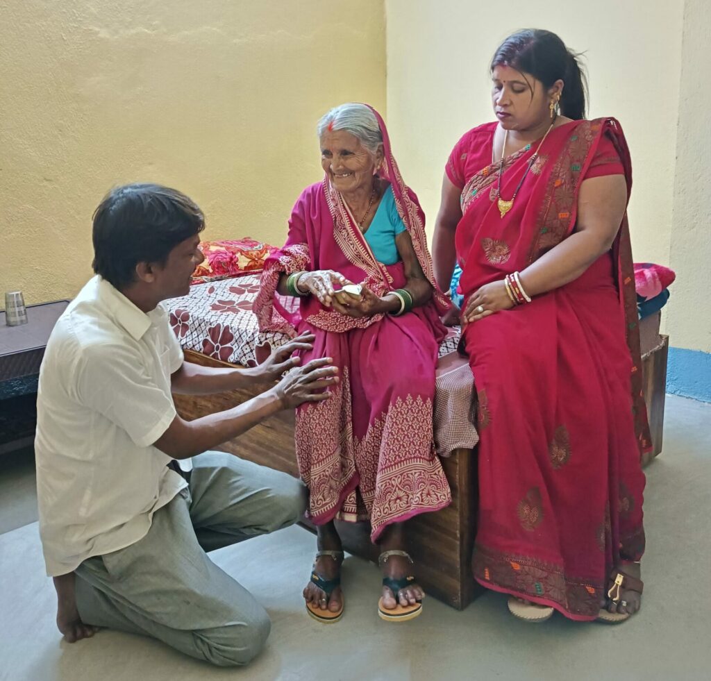 Installation d'une vielle femme dans sa chambre à l'école, rassurée par Rajesh et Sanghita.